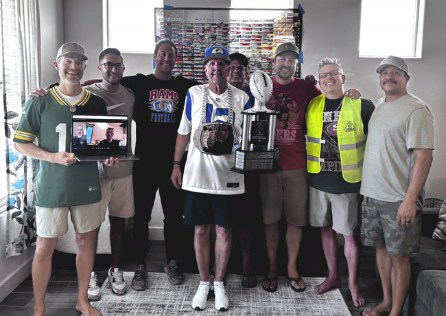 Eight owners around the championship trophy on 2026 draft day, two more joining by laptop